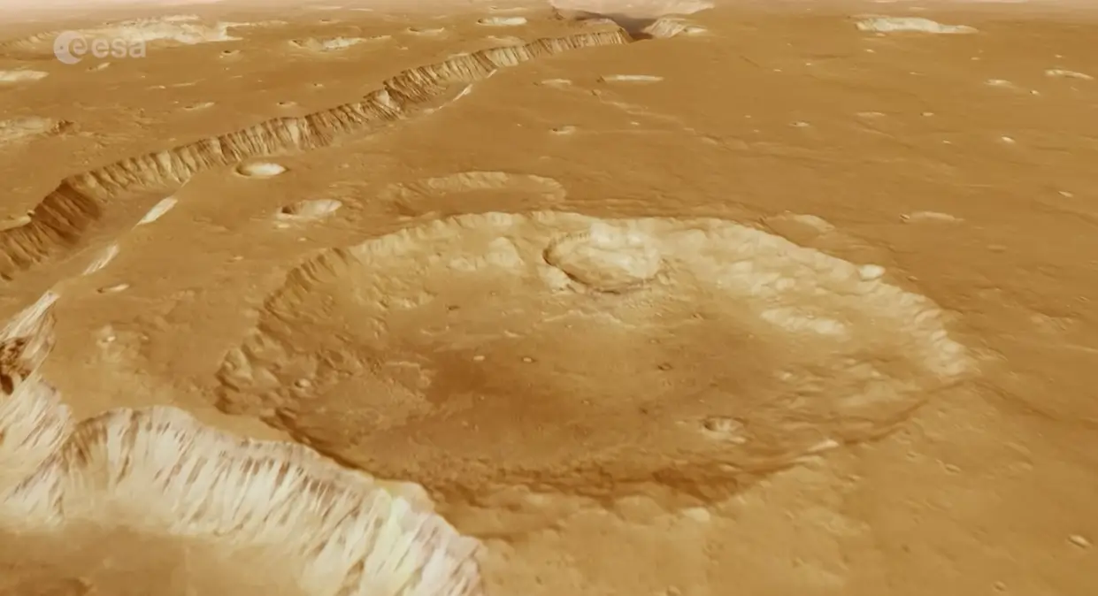 Eiropas Kosmosa aģentūra (ESA) publicējusi satriecošu video, kas ļauj skatītājiem “izlidot” virs seno ūdens straumju iezīmētā Marsa reģiona Xanthe Terra. Video tapis, izmantojot Mars Express orbītas zondes augstas izšķirtspējas kameras (HRSC) datus, kas vairāk nekā 20 gadus vāc informāciju par Sarkanās planētas virsmu. Senas upes gultnes un “haosa” ainavas Video centrālais objekts ir Shalbatana Vallis – dziļa ieleja aptuveni 1300 kilometru garumā, pa kuru pirms miljardiem gadu plūduši milzīgi ūdens apjomi no Marsa dienvidu augstienes uz ziemeļu līdzenumiem. Lidojuma laikā redzamas arī t.s. “haosa zonas” – savdabīgi, erozijas veidoti reljefi ar plato tipa salām un izlocītiem kalniem. Video noslēgumā skatītājus sagaida Da Vinči krāteris, kura diametrs sasniedz 100 kilometrus. Trīsdimensionāls ceļojums pa senu Marsu Video papildināts ar 3D reljefa modeli, kas balstīts uz topogrāfiskiem datiem, un atmosfēriskiem efektiem, lai skatījums būtu pēc iespējas reālistiskāks. Tas ļauj ieraudzīt senā Marsa klimatiskās pēdas – vietas, kur reiz plūda ūdens, veidojot kanjonus, deltas un plašas ielejas. Mars Express — 20 gadu ilgs darbs orbītā Mars Express ir vienīgais ESA aktīvais aparāts uz Marsa orbītas, un tas jau vairāk nekā divas desmitgades turpina atklāt planētas ģeoloģiskos un klimatiskos noslēpumus. Jaunākais video ne tikai parāda Marsa skaistumu, bet arī atgādina, cik dziļi un spēcīgi ūdens reiz ietekmējis šīs planētas virsmu.